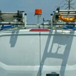 Rear of white HVAC truck with ladder racks and lighting.