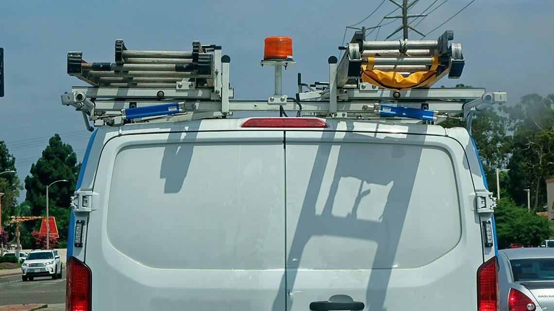 Rear of white HVAC truck with ladder racks and lighting.
