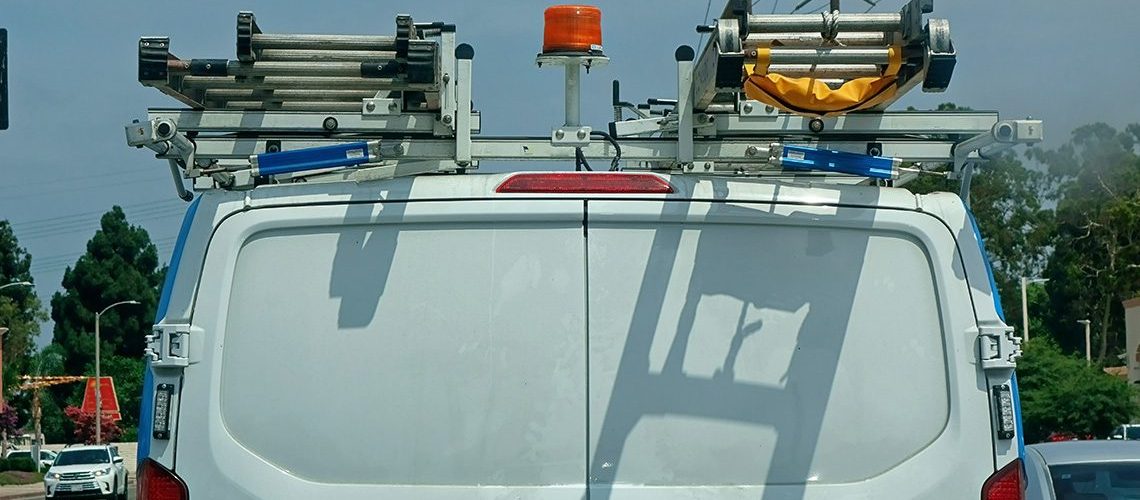 Rear of white HVAC truck with ladder racks and lighting.